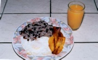 Costa Rican breakfast consisting of gallo pinto, fried plantains, an egg, and orange juice